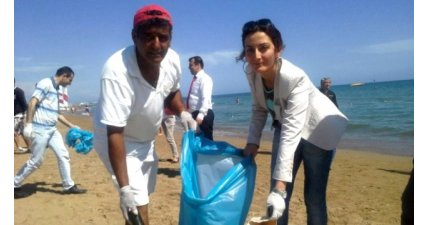 Otel çalışanları ve turistler birlikte plaj temizl